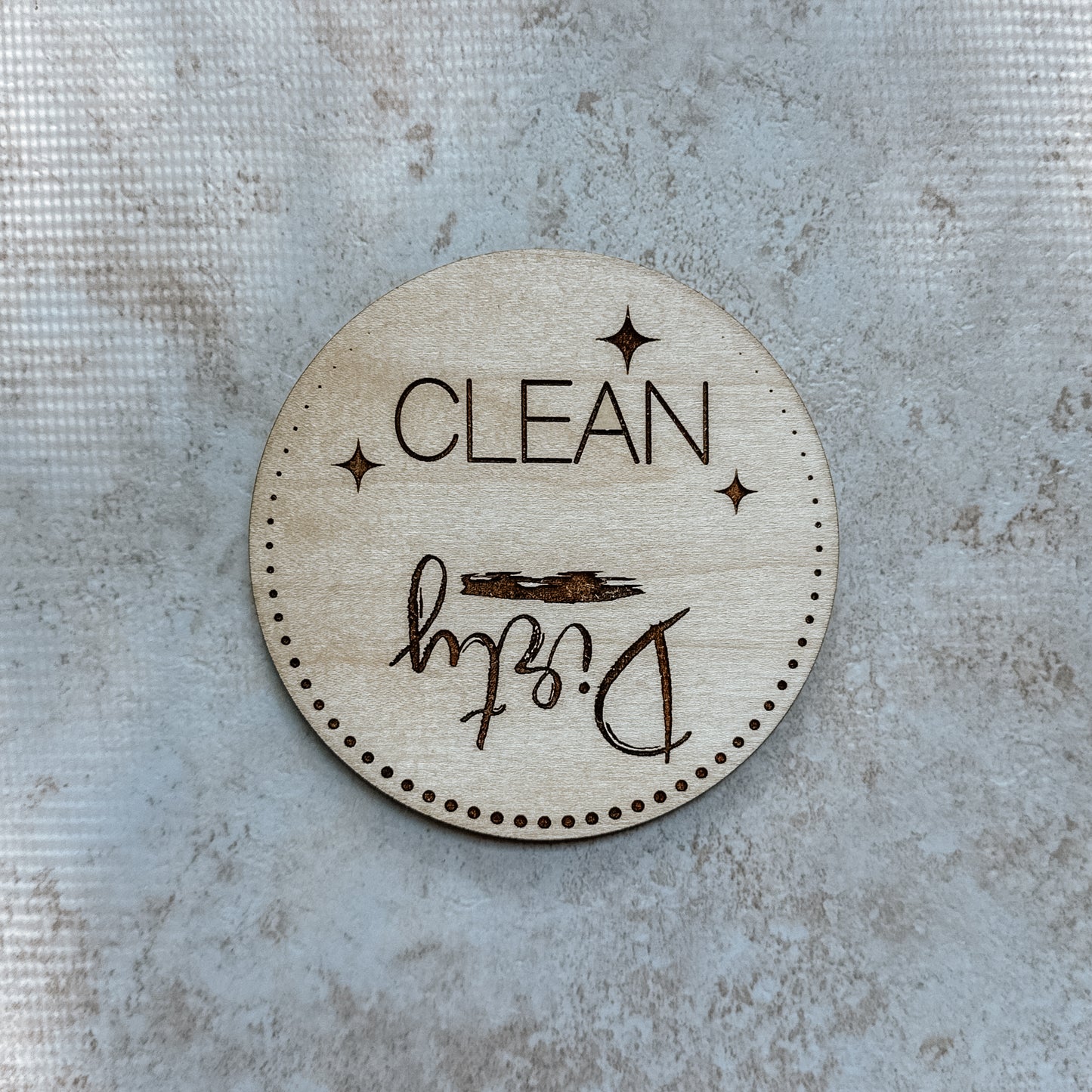 Round wooden sign with 'Clean' and 'Dirty' text on a textured surface