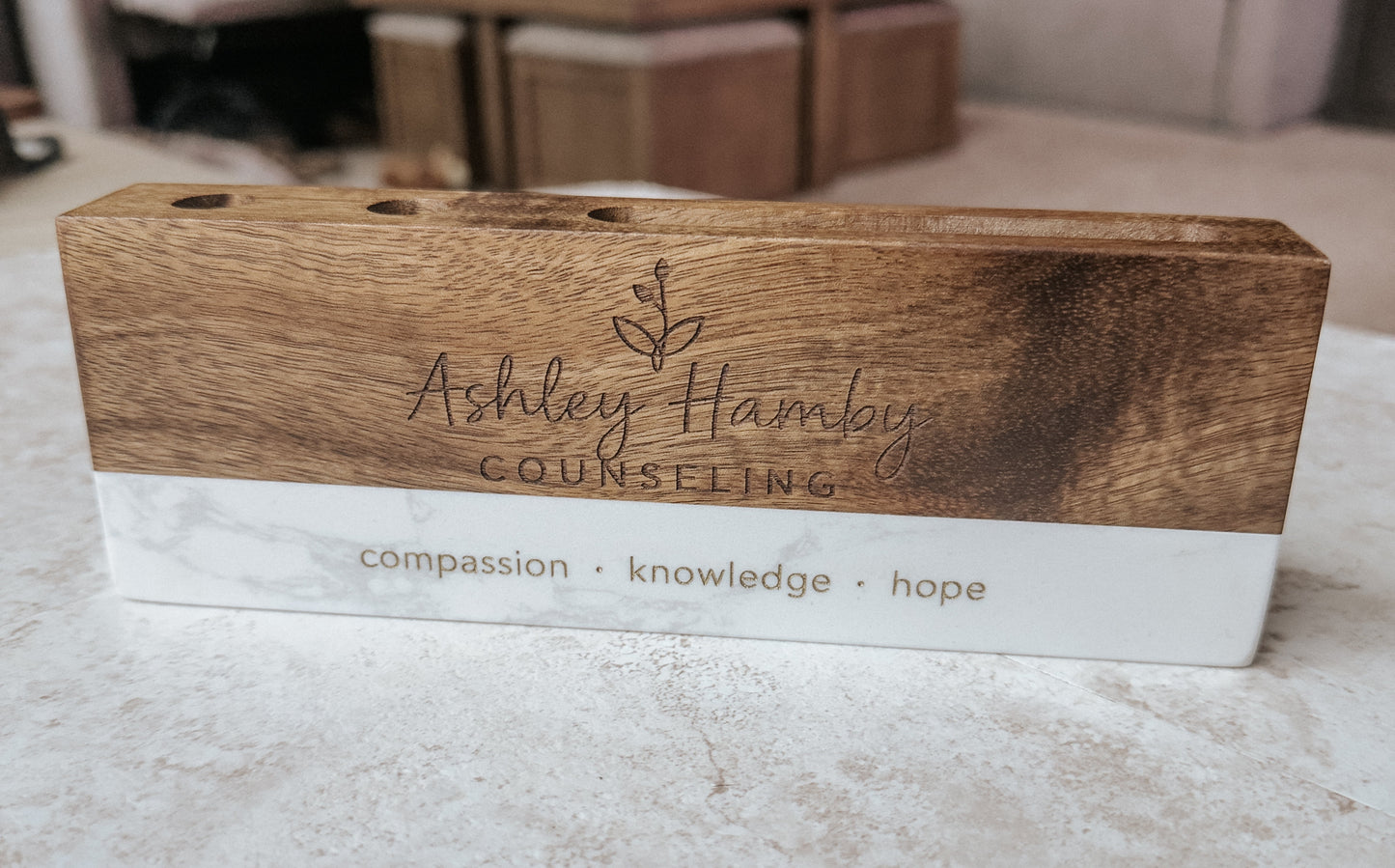 Wooden sign with 'Ashley Hamby Counseling' branding on a marble surface.