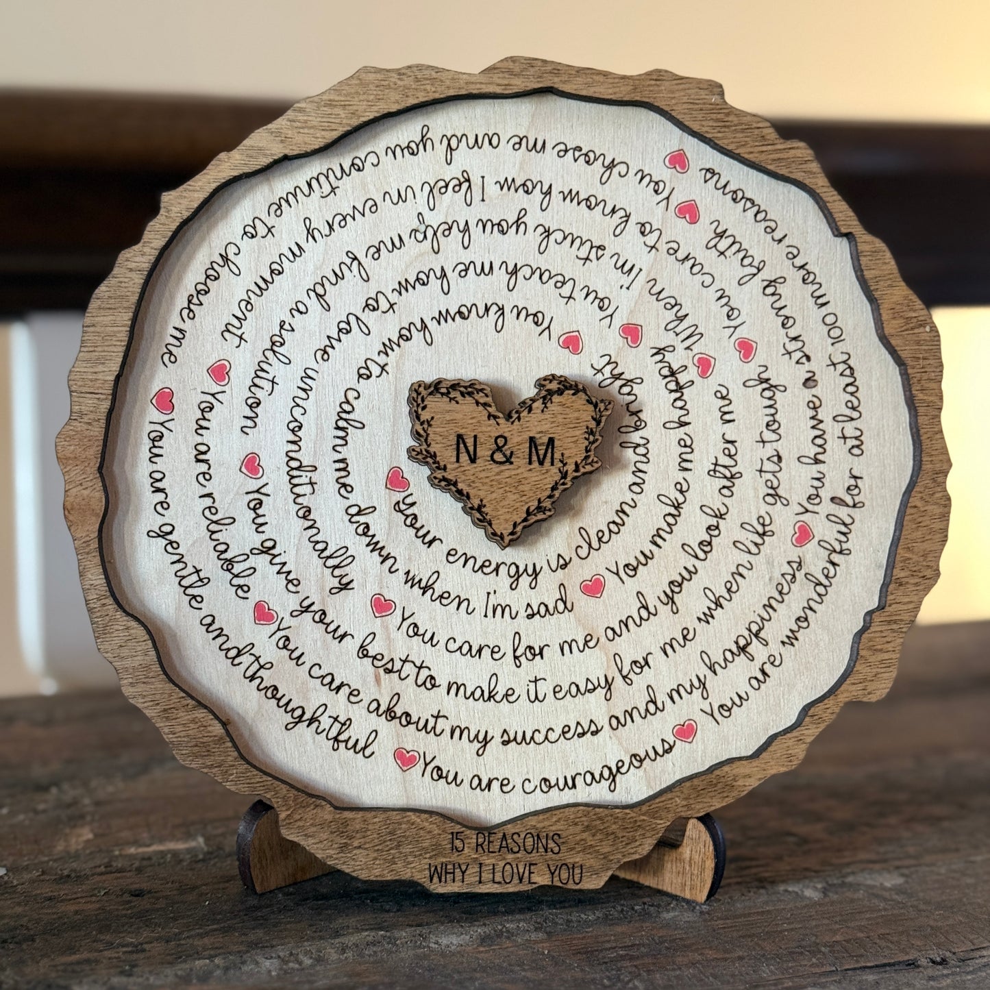 Close-up of engraved 15 Reasons I Love You wooden plaque with heart center initials and red hearts on a stand.