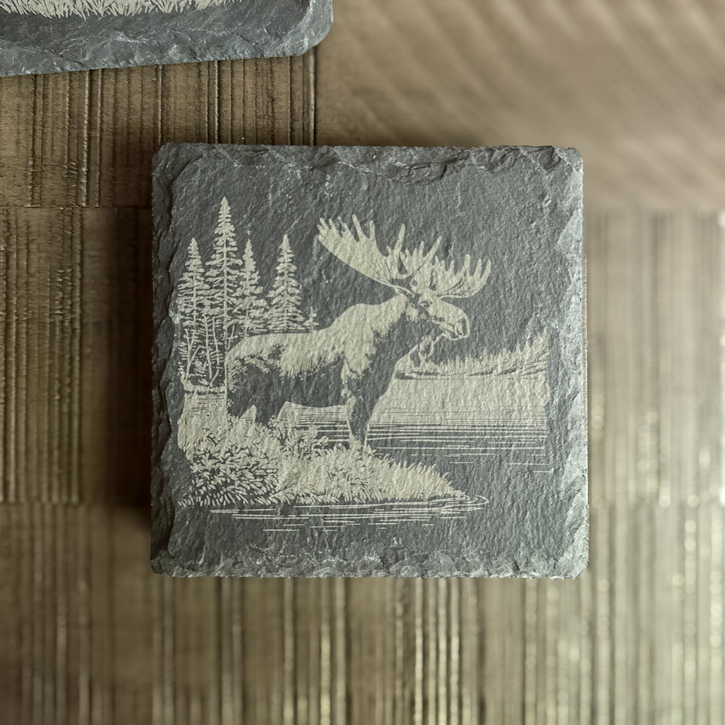 Engraved moose on slate coaster with pine trees – handcrafted cabin decor.