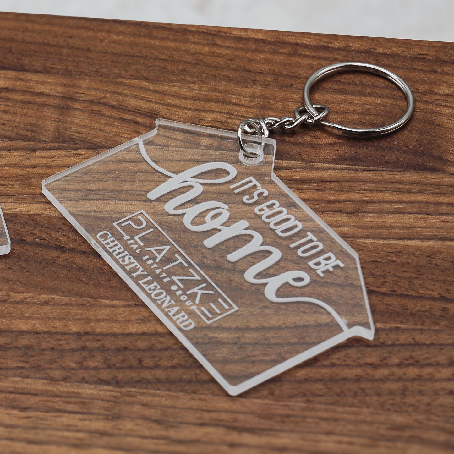 Two clear keychains with engraved text on a wooden surface
