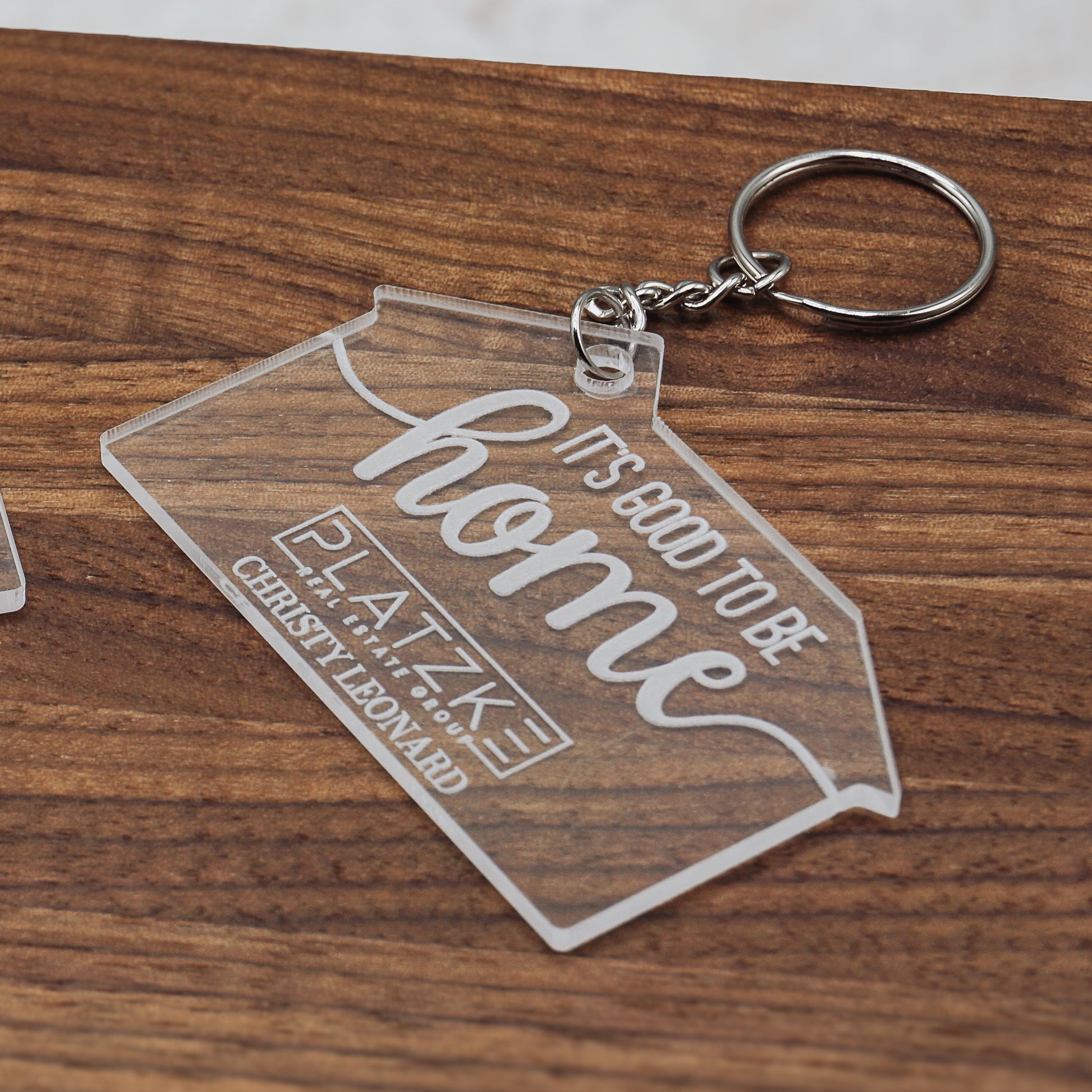 Two clear keychains with engraved text on a wooden surface