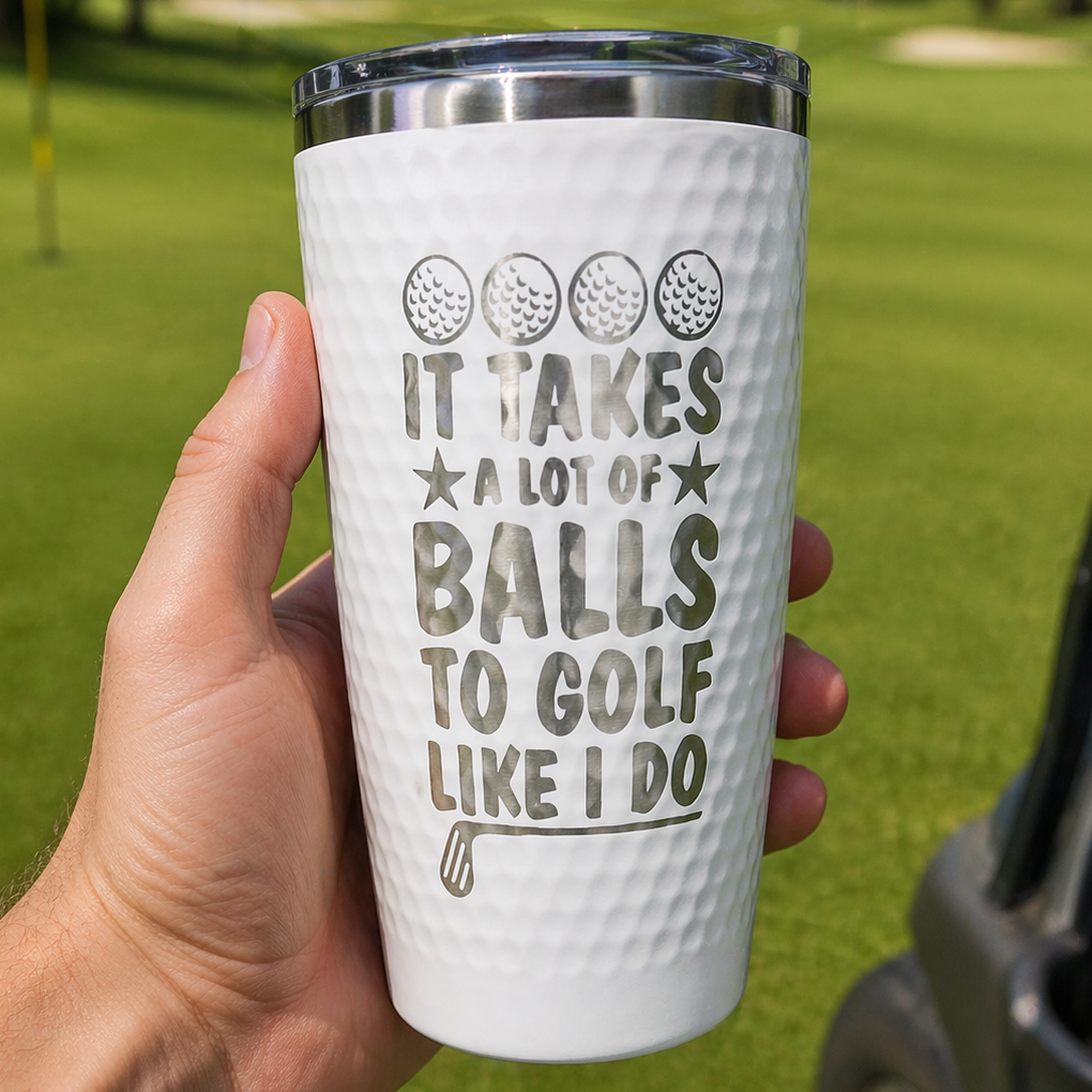 White tumbler with golf-themed text held in front of a golf course