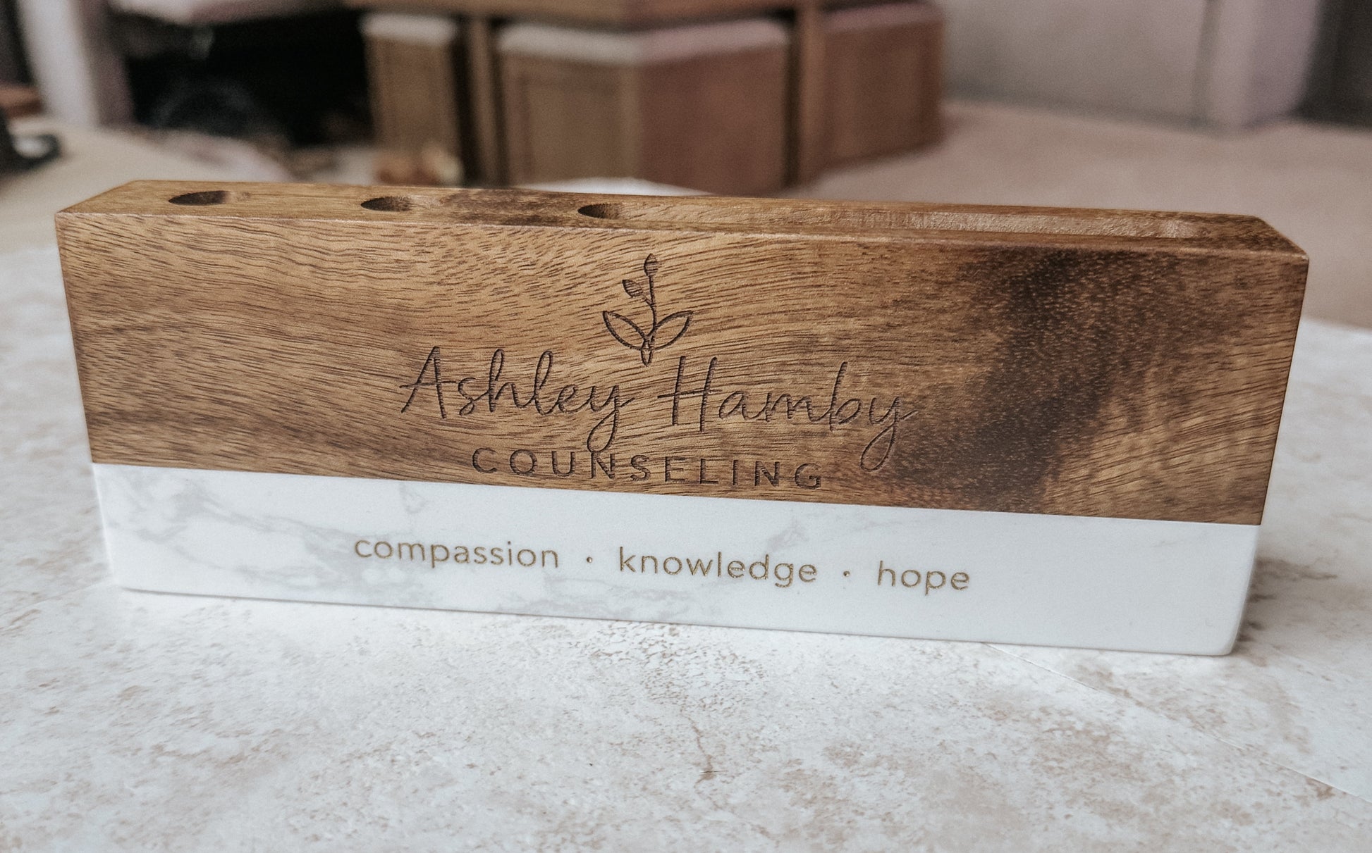 Wooden sign with 'Ashley Hamby Counseling' branding on a marble surface.
