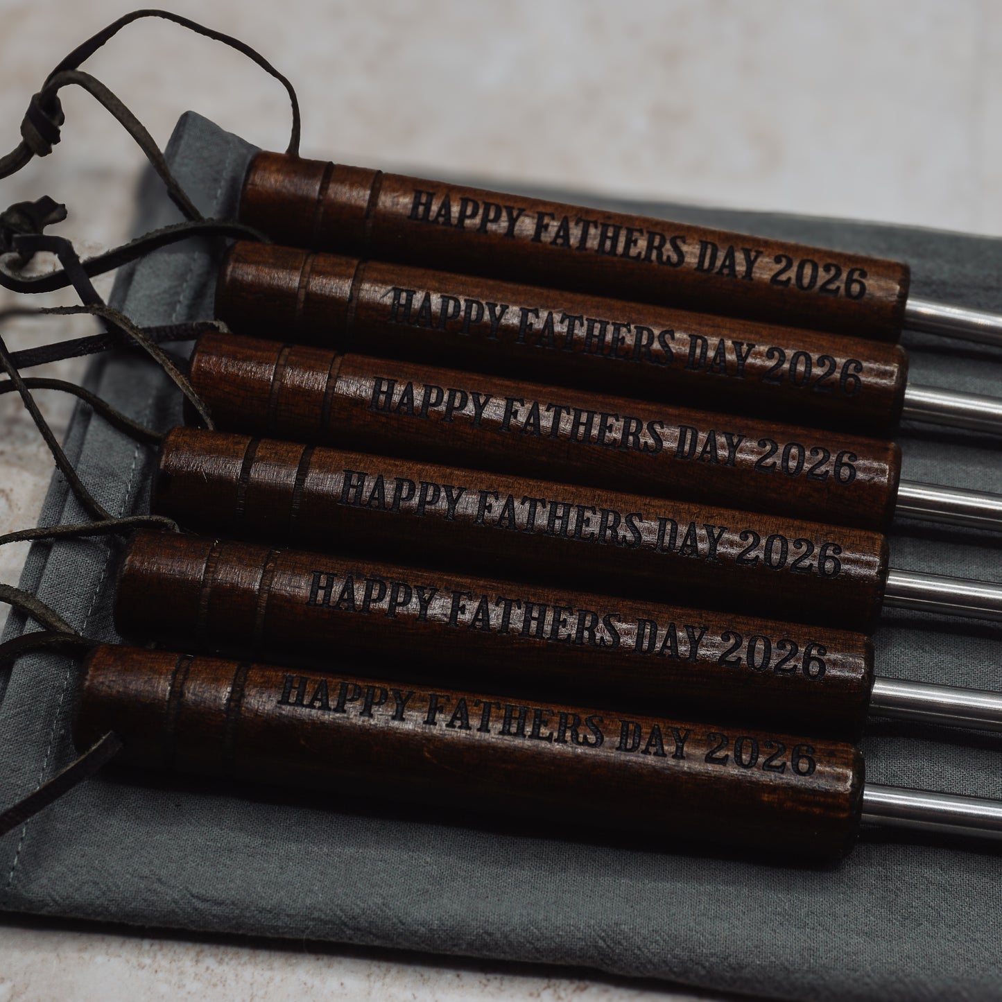 Wooden 'Happy Father's Day 2026' keychains on a gray surface