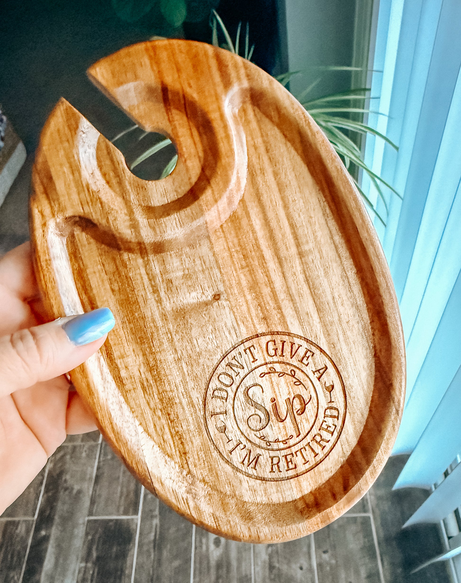 Wooden tray with 'I Don't Give a Sip, I'm Retired' engraving held by a hand.