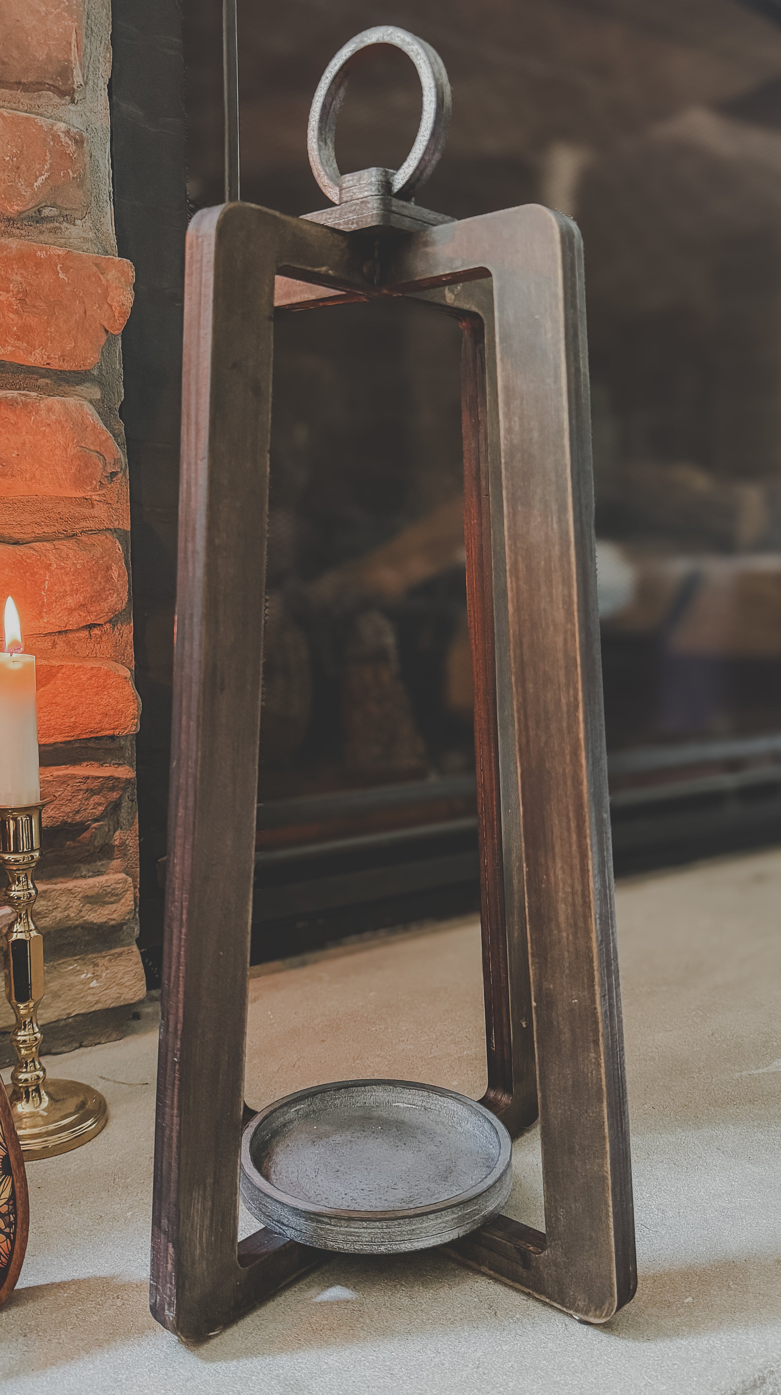 Decorative wooden lantern, placed against a brick wall.