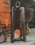 Wooden lantern with a candle in front of a stone fireplace