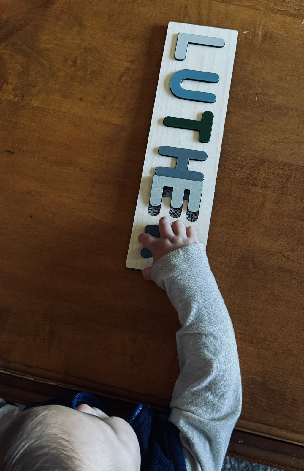 Baby playing with personalized wooden name puzzle – handcrafted toddler gift
