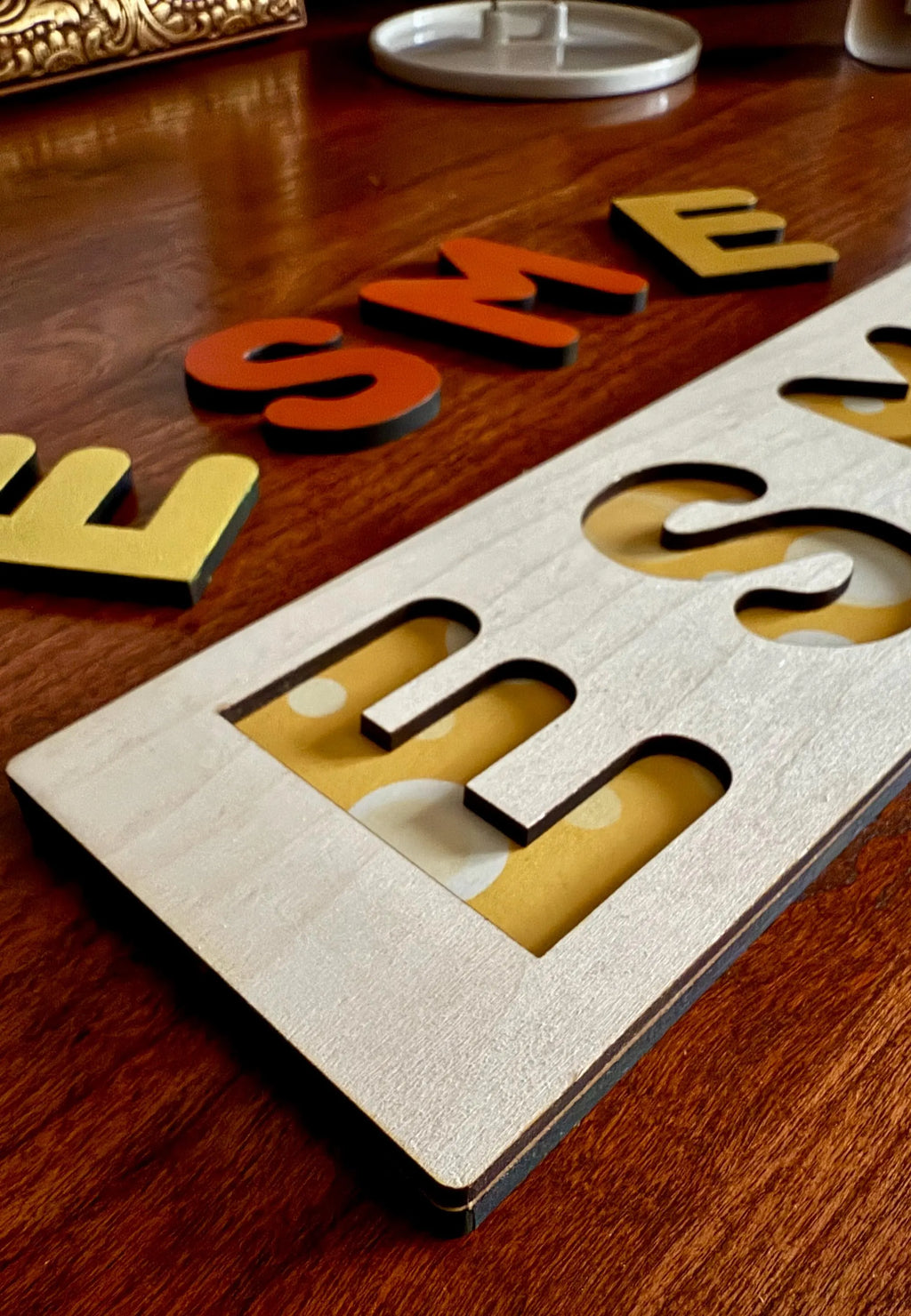 Angled wooden name puzzle with yellow polka dot backing and colorful letters – personalized toddler gift