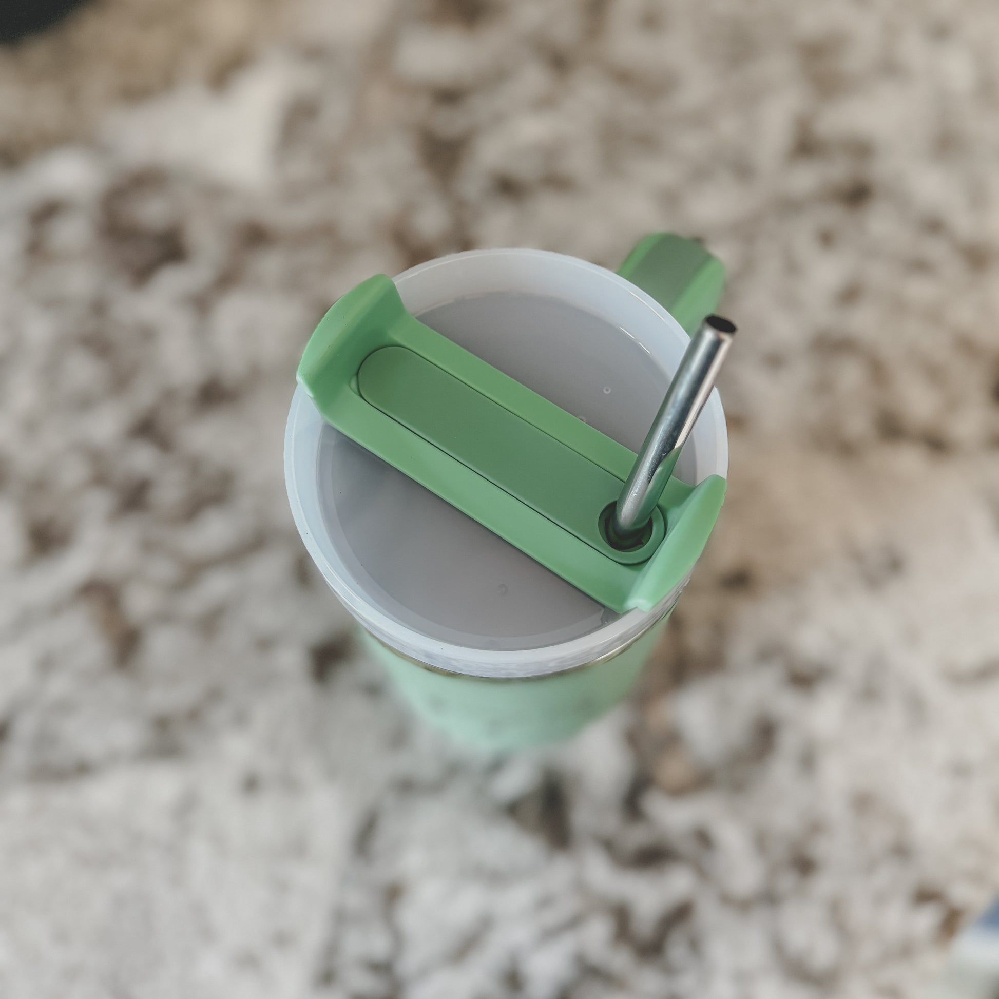 Top view of mint green 40oz tumbler with stainless steel straw and screw-on lid, on a marble countertop

