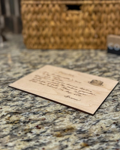 Engraved wooden recipe card featuring a handwritten pancake recipe, displayed on a granite countertop