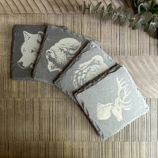Set of 4 engraved slate coasters featuring detailed animal profiles – wolf, bison, owl, and elk – rustic wildlife decor