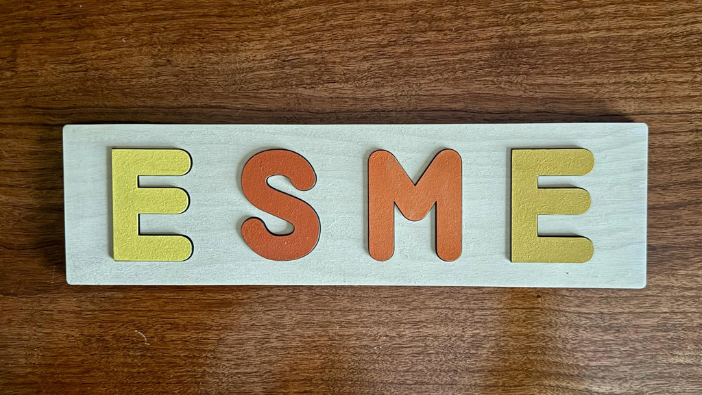 Finished wooden name puzzle with colorful letters spelling ESME – personalized baby gift