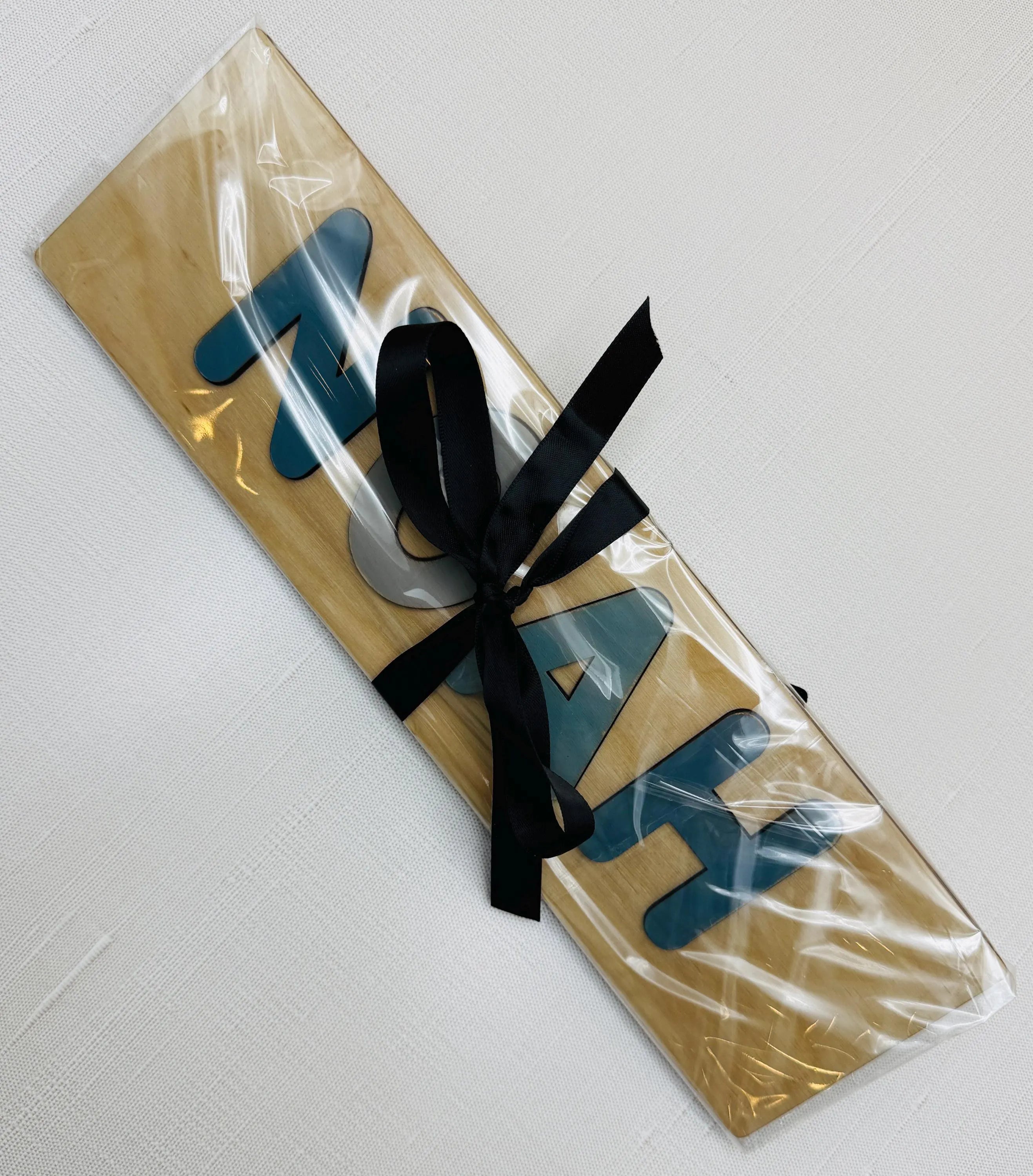 Personalized wooden name puzzle wrapped in clear gift packaging with black ribbon – ready to gift