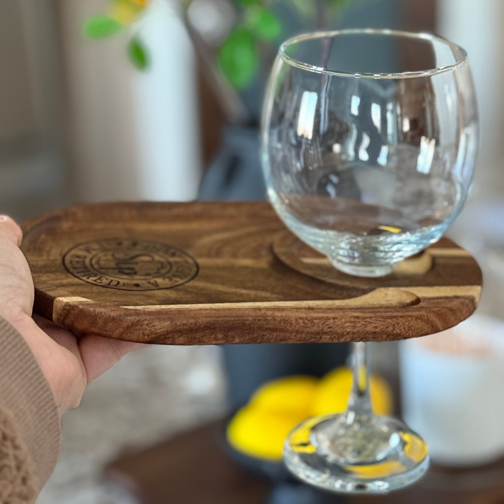 Wooden tray with a glass holder containing a clear glass on a blurred background