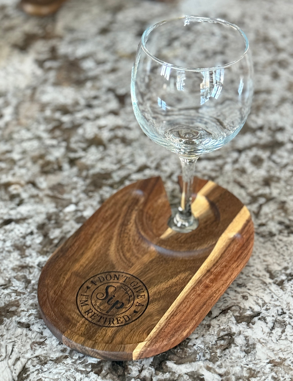 Engraved acacia wine caddy holding a glass on a granite countertop