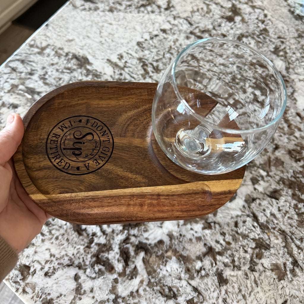 Engraved acacia wood wine caddy held in hand with a glass, shown on a granite surface