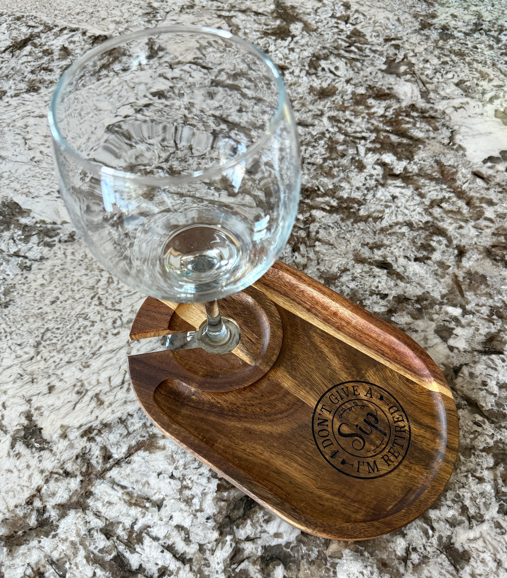 Wine glass placed in an engraved acacia wood snack tray on a marble countertop