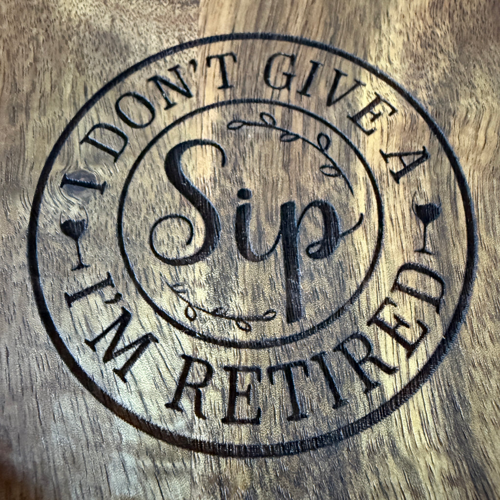 Up-close engraving of "I Don't Give a Sip, I'm Retired" text on a wooden wine caddy