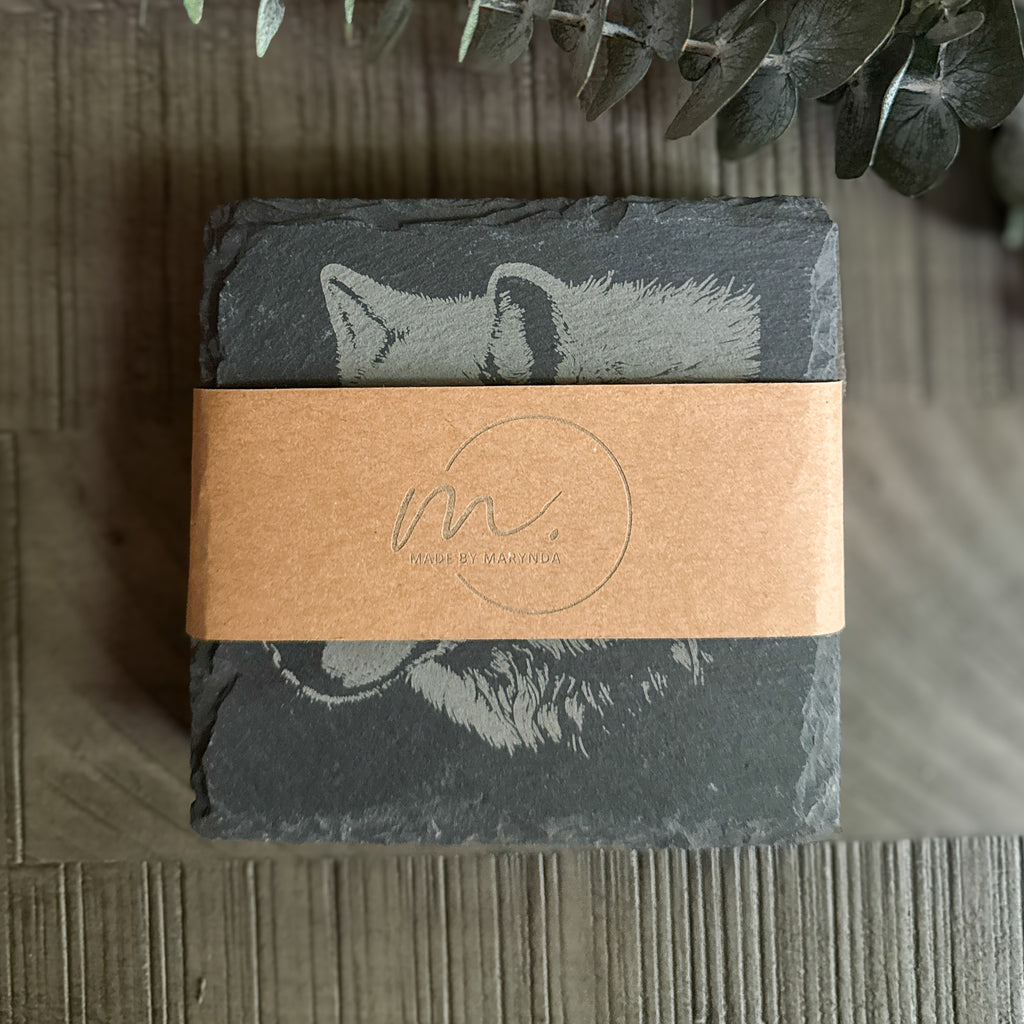Stack of engraved wildlife profile slate coasters wrapped in kraft band with Made by Marynda logo – rustic gift packaging
